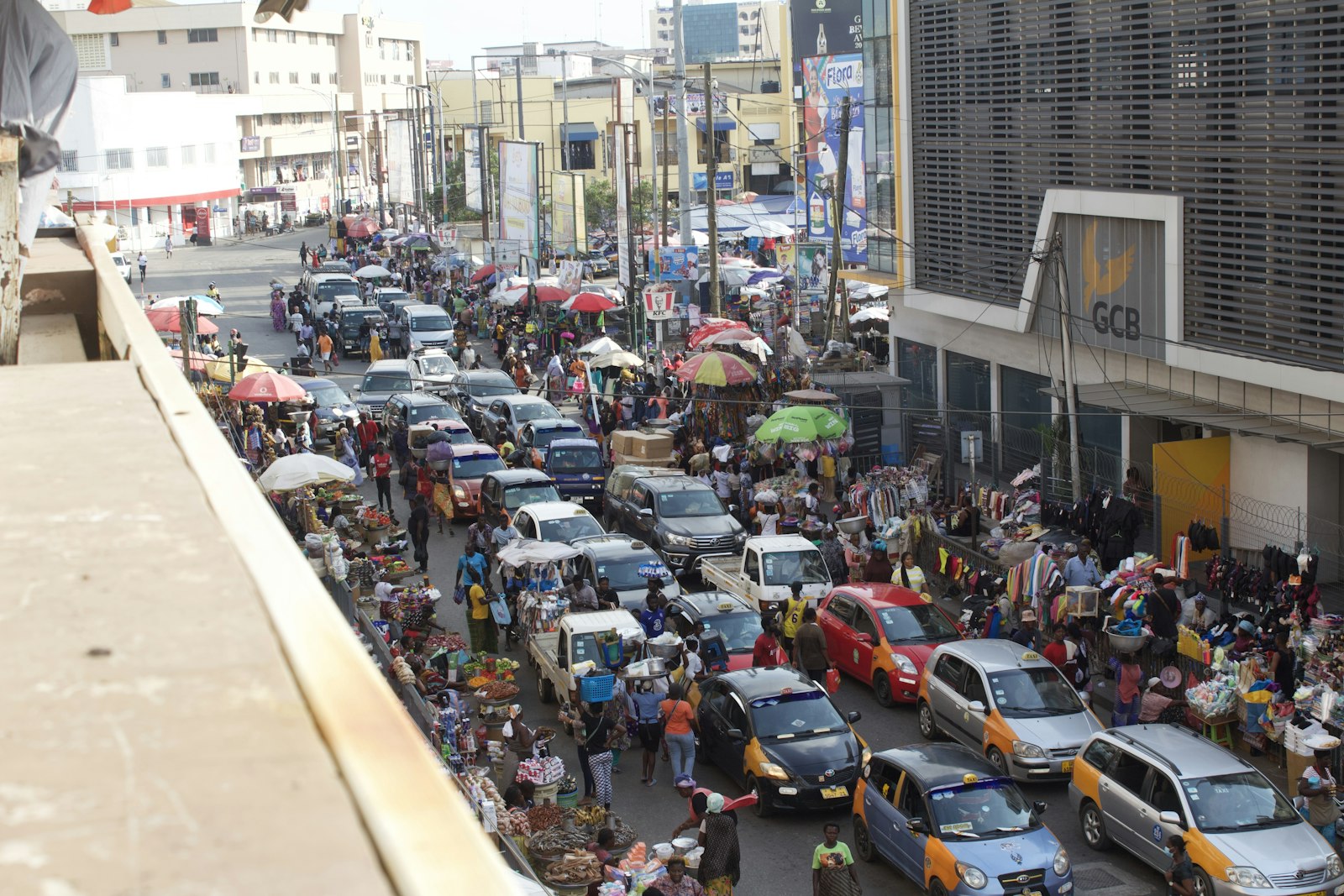 Overhead view of a busy Accra street with taxis and market umbrellas