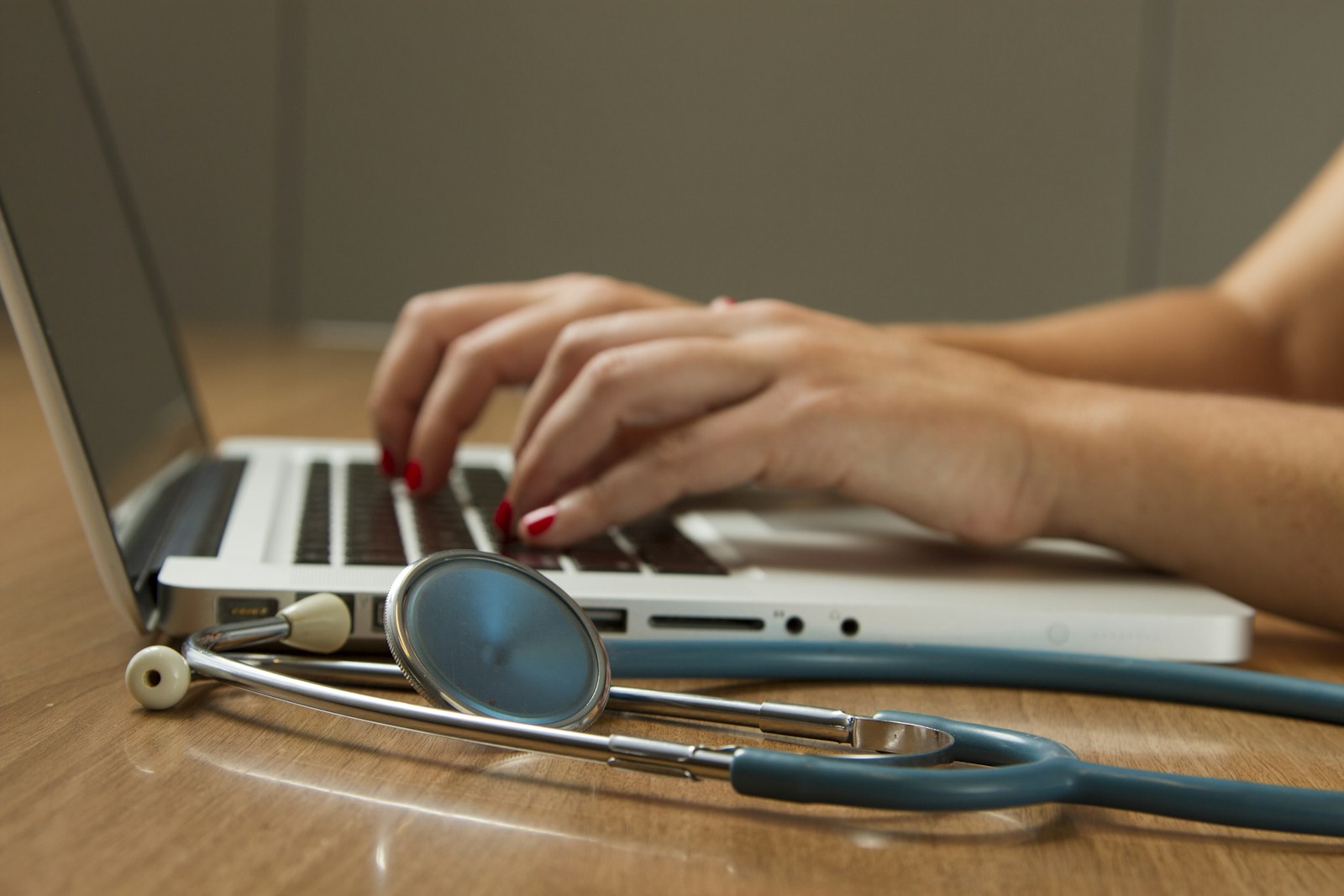 Stethoscope on a desk beside a laptop in use